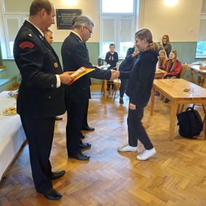 Zuzanna Kałuża odbiera dyplom z rąk przedstawicieli Państwowej Straży Pożarnej w Brzesku. Kliknięcie na zdjęcie spowoduje jego powiększenie do rozmiaru oryginalnego.